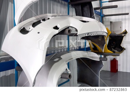 Bumpers hanging in auto service shop after painting and drying 87232863