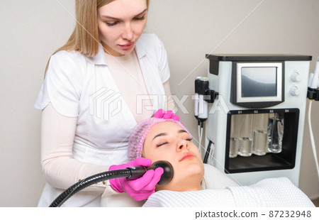 Young woman receiving treatment in cosmetology clinic. Cosmetology skin care. Aesthetic facial treatment Concept. Young woman receiving treatment in cosmetology clinic. Cosmetology skin care. Aesthetic facial treatment Concept. 87232948