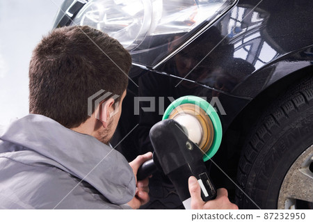 Man using polisher to polish black car body in the workshop Man using polisher to polish black car body in the workshop 87232950