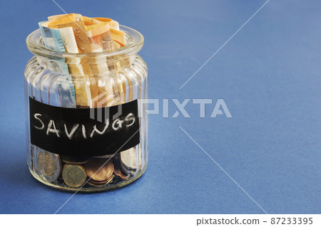 saving bottle with euro notes coins blue background saving bottle with euro notes coins blue background 87233395
