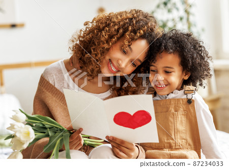 Young ethnic woman getting congratulations from son on Mothers day Young ethnic woman getting congratulations from son on Mothers day 87234033
