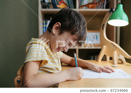 A schoolboy doing math lesson sitting at desk in the children room 87234066
