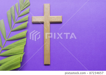 Cross and palm leaves on purple background. Lent season concept. 87234657