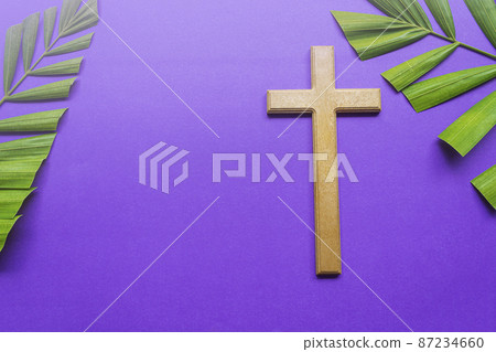 Cross and palm leaves on purple background. Lent season concept. 87234660