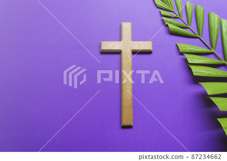 Cross and palm leaves on purple background. Lent season concept. 87234662