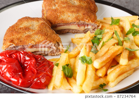 cachopo consists simply of two breaded veal fillets stuffed with cheese and Serrano ham with french fries closeup in the white plate. Horizontal cachopo consists simply of two breaded veal fillets stuffed with cheese and Serrano ham with french fries closeup in the white plate. Horizontal 87234764