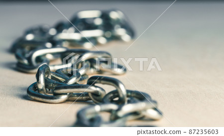 Metal iron chain slowly falls on a wooden table Metal iron chain slowly falls on a wooden table 87235603