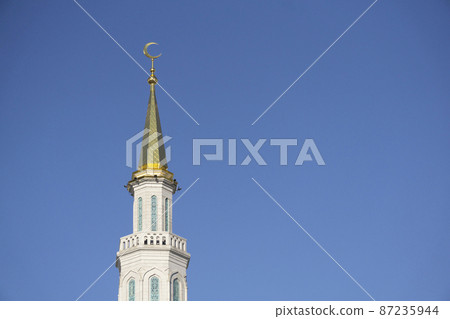Minaret of a Muslim mosque on a background of blue sky. Muslim and Islamic architecture 87235944