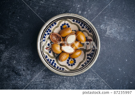 Argan seeds on a dark background. Argan oil based cosmetics concept. Argan seeds on a dark background. Argan oil based cosmetics concept. 87235997