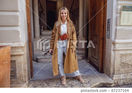 Full-length photo of woman standing at the entrance to building 87237104