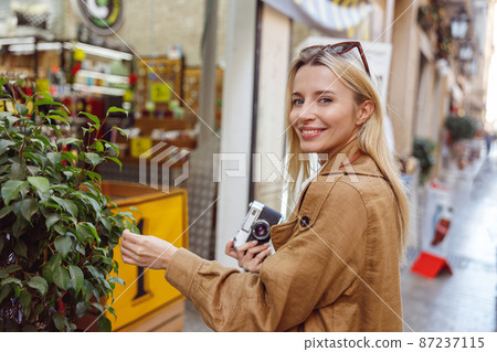 Charming lady looking at camera while touching plant leaf 87237115