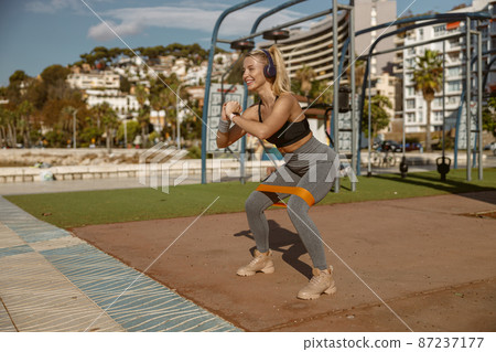 Young attractive woman stretching exercising equipment outdoors 87237177