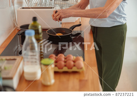 Senior woman cooking at glass-ceramic stove in kitchen Senior woman cooking at glass-ceramic stove in kitchen 87237221
