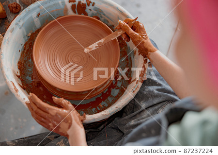 Potter working manually on pottery wheel in workroom Potter working manually on pottery wheel in workroom 87237224