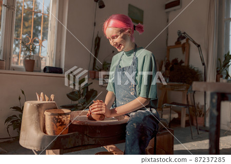 Young potter working with clay in workroom Young potter working with clay in workroom 87237285