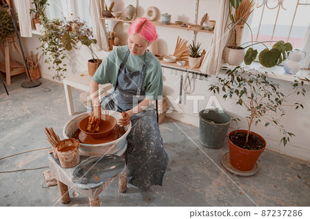 Young potter working on pottery wheel in workroom Young potter working on pottery wheel in workroom 87237286