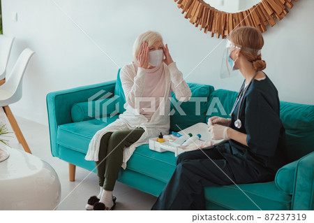 Nurse checking health of senior woman in living room Nurse checking health of senior woman in living room 87237319