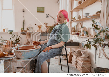 Cute potter creating ceramic bowl on circle in workroom 87237326