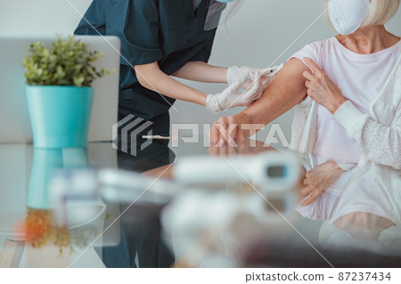 Senior woman getting vaccination at her home 87237434