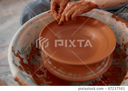 Skillful woman works on pottery wheel in ceramics workshop Skillful woman works on pottery wheel in ceramics workshop 87237501