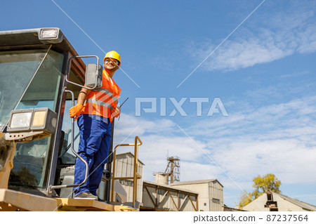 Multiracial construction worker using heavy machinery in plant 87237564