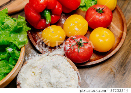 a wooden bowl of flour and vegetables on the kitchen table. farm products 87238244