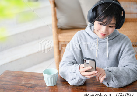 A woman staring at a smartphone while listening to music. A bird's-eye view with front blur and copy space. A woman staring at a smartphone while listening to music. A bird's-eye view with front blur and copy space. 87238656
