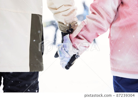 Parents and children holding hands at the ski resort 87239304