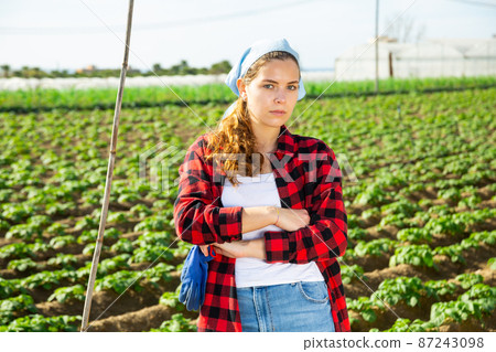 Confident girl farmer on vegetable farm field in spring 87243098