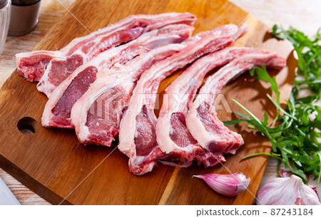 Raw mutton chops on wooden cutting board with herbs and spices 87243184
