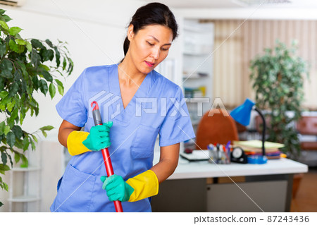 Woman wiping office floor with mop 87243436