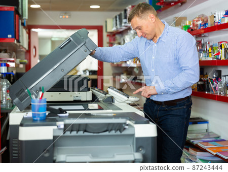 Confident businessman using printer in office Confident businessman using printer in office 87243444