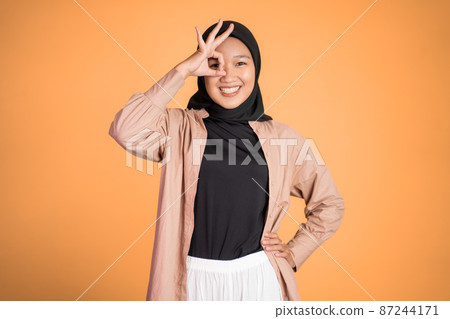 muslim woman in hijab showing oke gesture with hands imitating binoculars 87244171