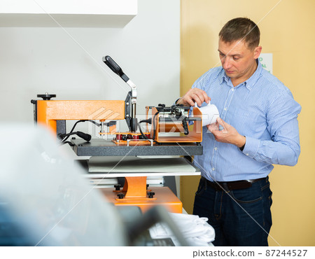 Man printing on coffee mugs in workshop Man printing on coffee mugs in workshop 87244527