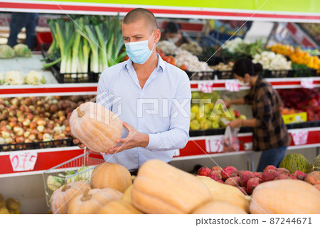 Man in mask with pumpking in greengrocer Man in mask with pumpking in greengrocer 87244671