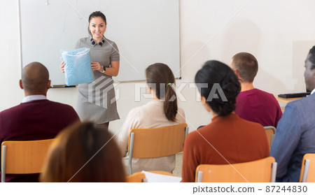 Female coach presents the product in audience at business training 87244830