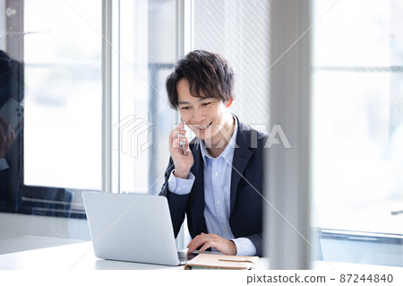 一邊看商務電腦一邊打電話的男人 一邊看商務電腦一邊打電話的男人 87244840