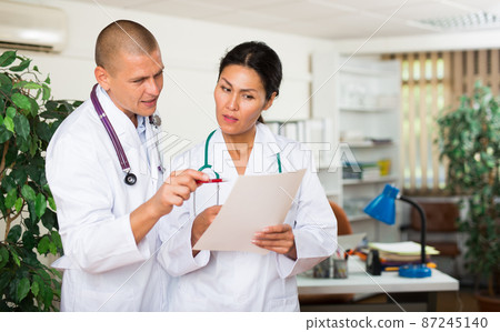 Two doctors discussing about medical report 87245140