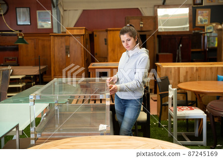 Woman chooses table in furniture store Woman chooses table in furniture store 87245169