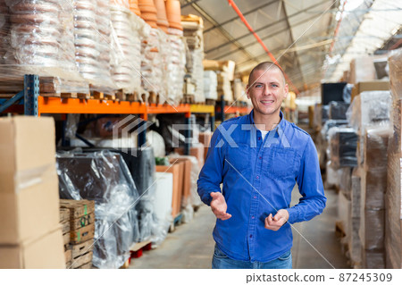Portrait of positive man in blue shirt in store warehouse 87245309