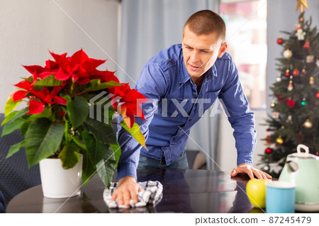 Man cleaning table with rag at home before christmas Man cleaning table with rag at home before christmas 87245479