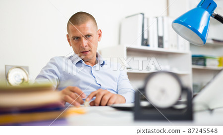 Carefree office worker playing with coin at workplace 87245548