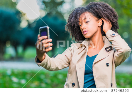 young afro hair Latin woman selfie in winter clothes with smartphone Dominican Republic lifestyle young afro hair Latin woman selfie in winter clothes with smartphone Dominican Republic lifestyle 87246293