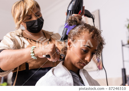 Makeover haircut in beauty salon with Latin hairdresser professional. mixed race with facemask 87246310