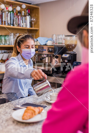 Latin young woman serving a coffee in a bistro to an senior adult Hispanic man. Peruvian restaurant Latin young woman serving a coffee in a bistro to an senior adult Hispanic man. Peruvian restaurant 87246328