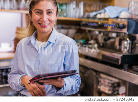 small business woman owner using tablet technology. young Peruvian Latinx bistro entrepreneur 87246342