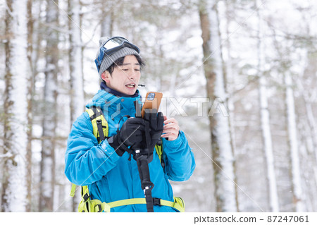 A man looking at a smartphone in a snowy mountain A man looking at a smartphone in a snowy mountain 87247061