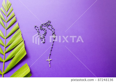 Cross and palm leaves on purple background. Lent season concept. 87248136