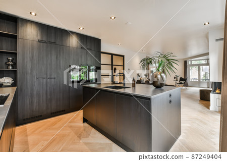 Modern kitchen with black furniture and wooden floor 87249404