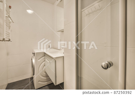 Washing machine in a compact bathroom with a small sink Washing machine in a compact bathroom with a small sink 87250392